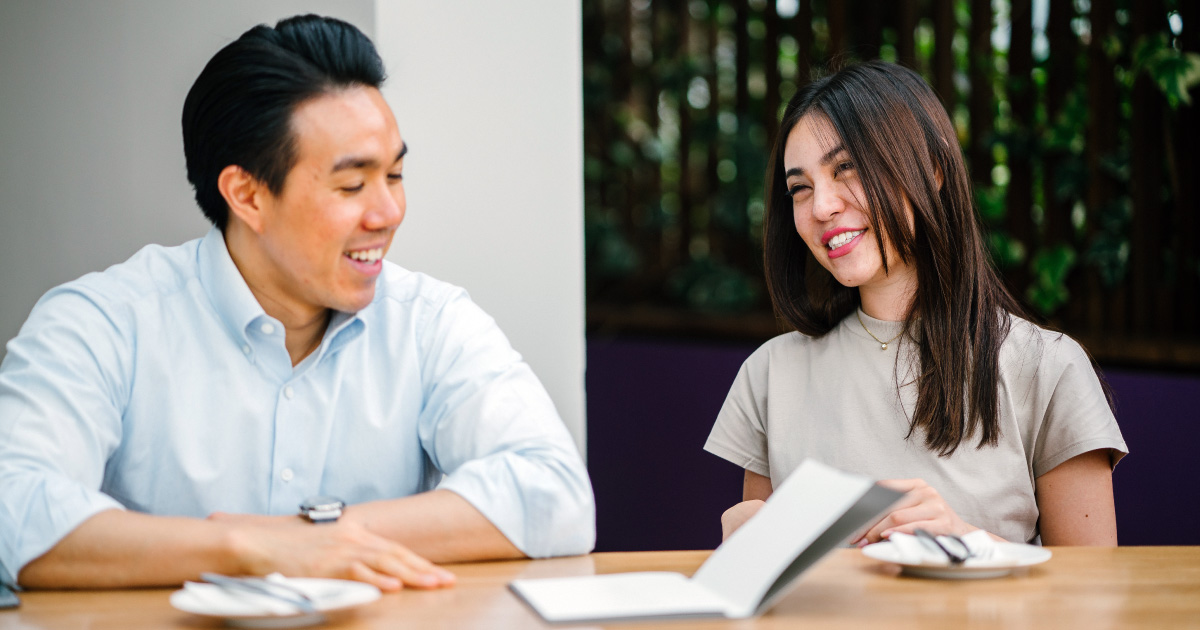 Two people at a desk smile while reading the definitive guide to sales enablement