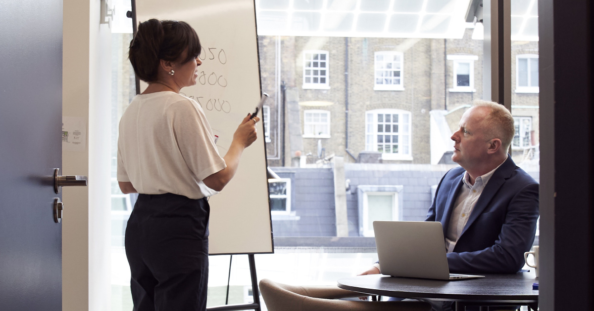 Person holding whiteboard pen presents to a sitting audience