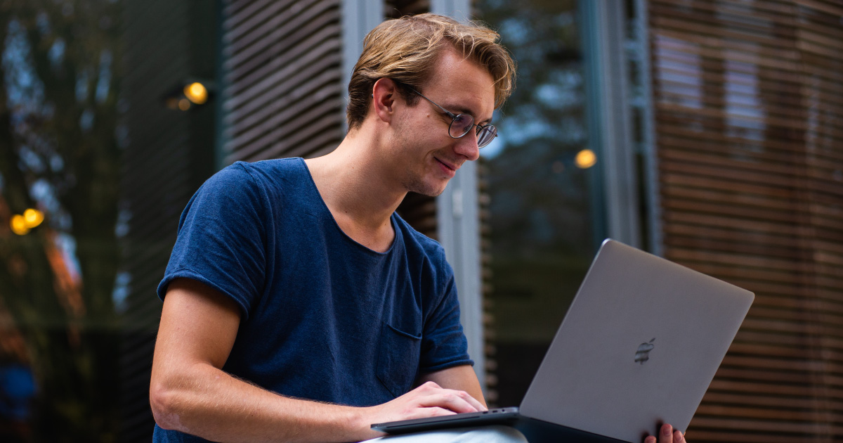 Person wearing glasses smiles at laptop