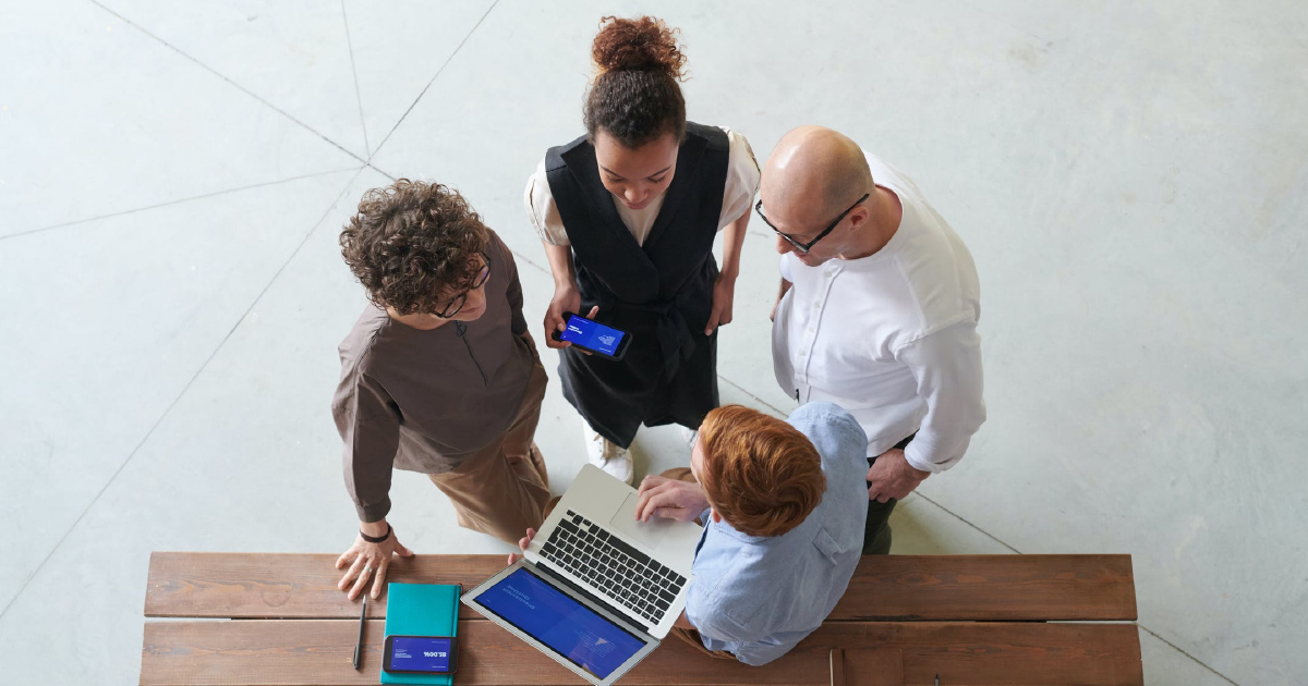 Team of four gathers around laptop to connect sales enablement platform to CRM