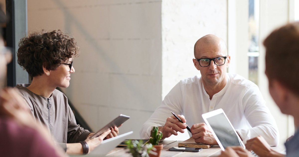 Four people sitting around a desk look at each other