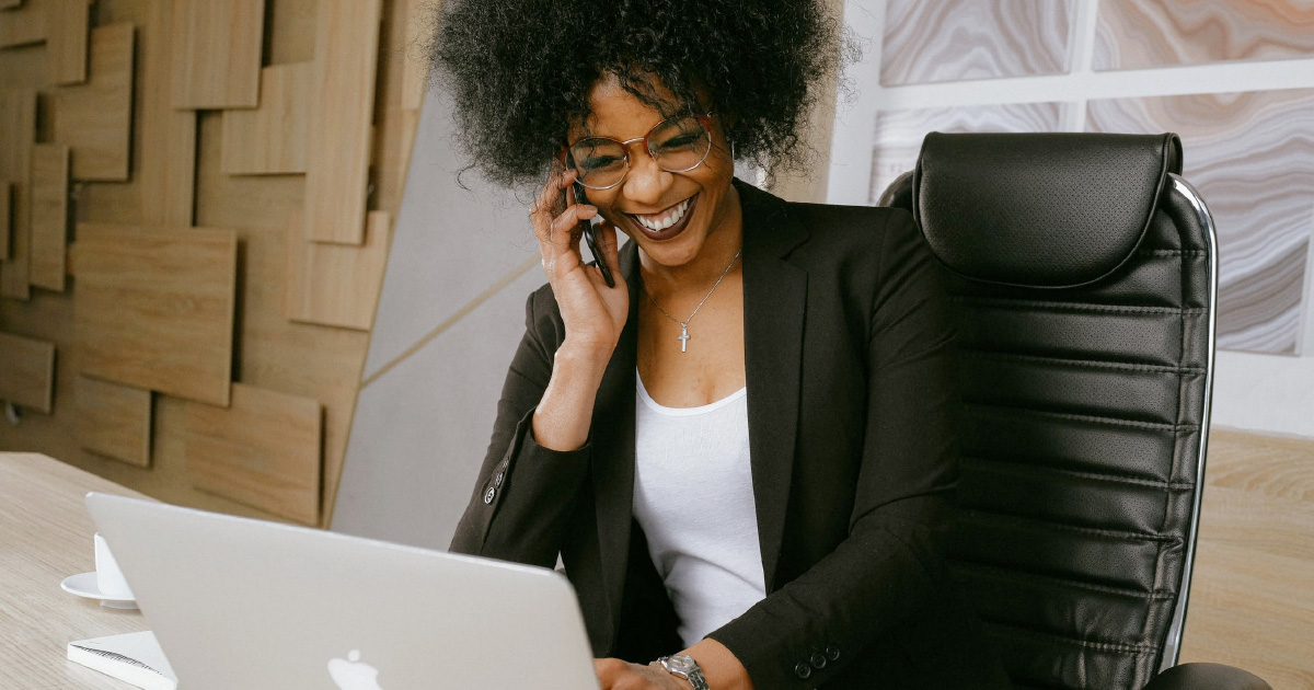 Person on cellphone smiles and looks at computer