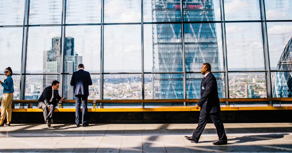 People in suits walk in front of glass window