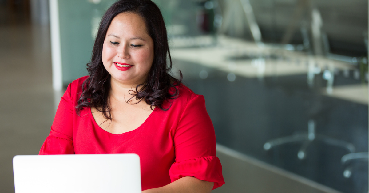 Person in red blouse smiling at computer