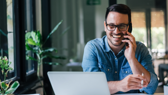 Smiling person on cellphone in front of computer