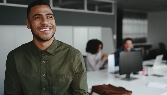 Person smiles into distance while others at a desk talk