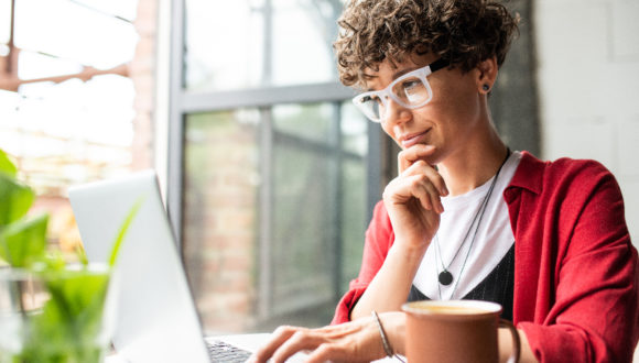 Person holds chin while looking at computer