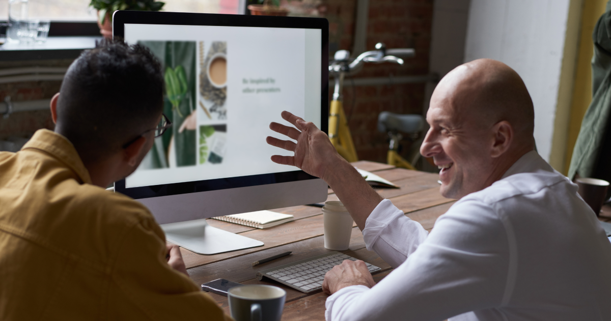 Two people smile while looking at sales portal on desktop screen