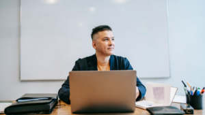 A person contemplating the future of sales while smiling in front of a computer