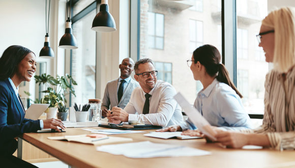 People smiling around a desk while collaborating on content