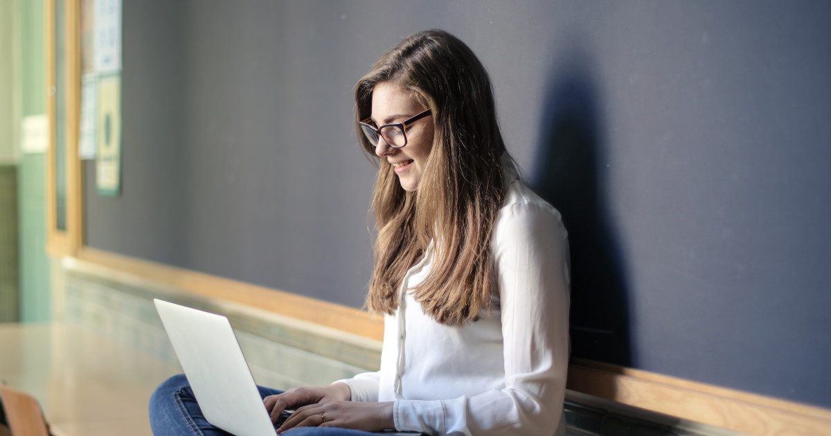 Person with glasses smiles at laptop screen