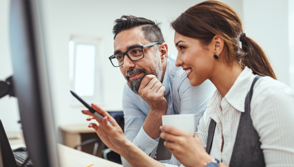 Two people smile at a computer