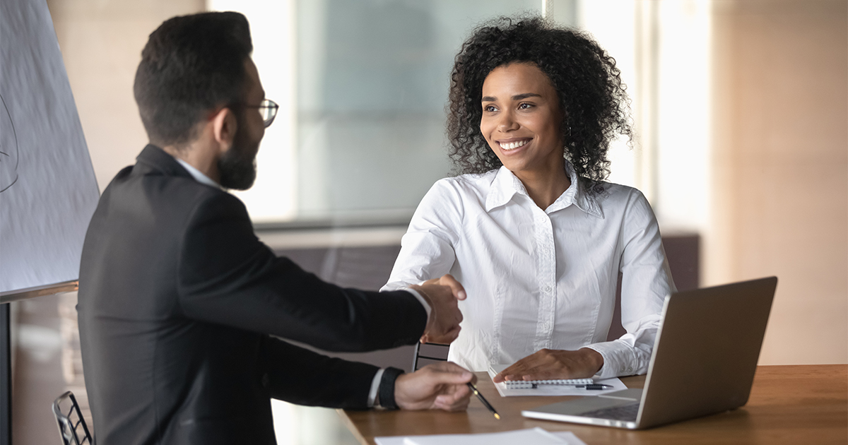 Two smiling people shake hands