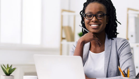 Person at computer holds pen and smiles