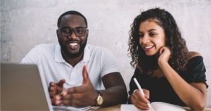 Two people smile at a computer