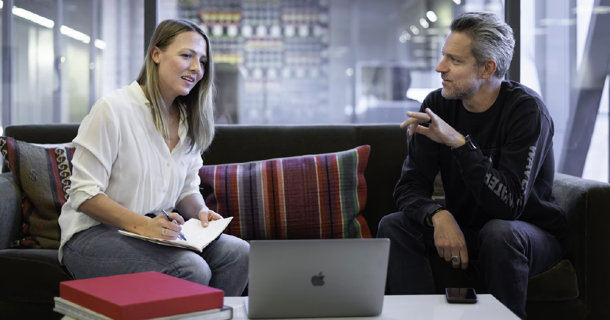 two people sit and talk in front of a computer