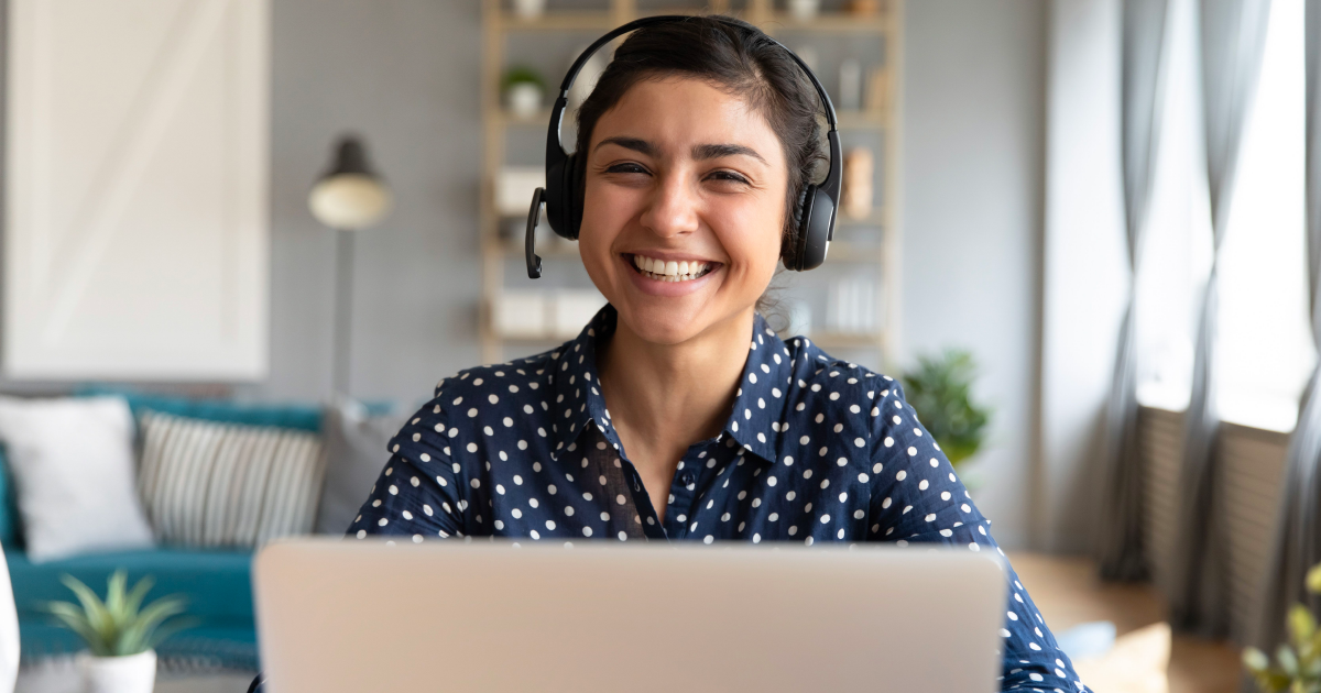 Person wearing headset in front of computer smiles