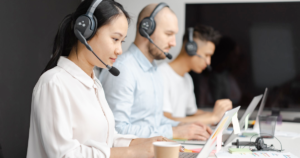 Salespeople wearing headsets typing in front of computers